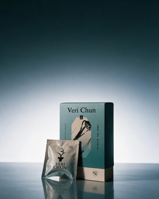 Qing Ping tea box and silver sachet on a reflective blue surface